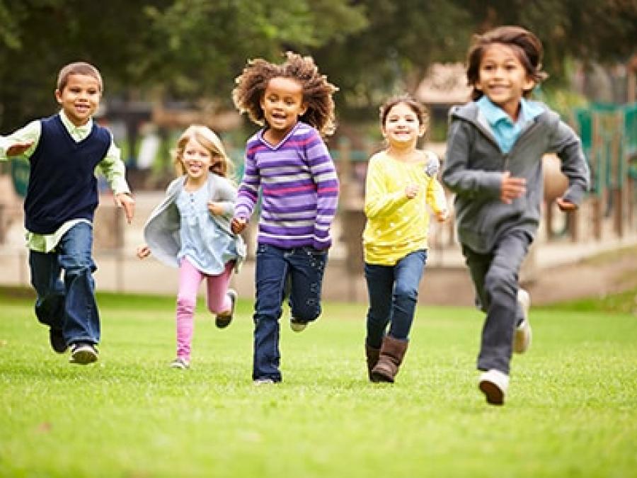 Children running towards the camera smiling in a park
